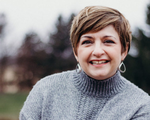 A woman with short hair wearing a sweater.